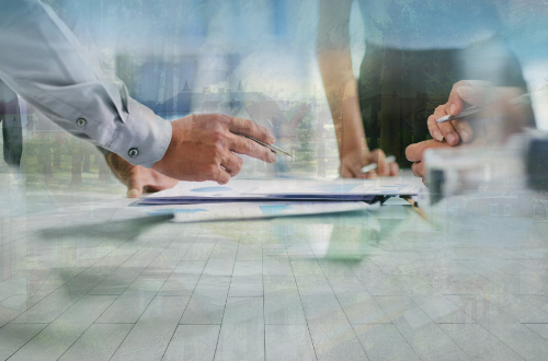Business people gathered around a table, pens to paper.